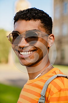Young black man wearing piercing and sunglasses walking in park