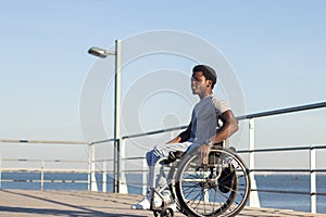 Young Black man in wheelchair enjoying spending time at seashore photo