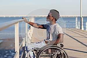 Young Black man in wheelchair looking at seascape photo