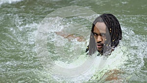 A Young Black Man Withstand Flowing Water With His Back in a River