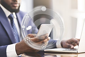 Young black man working in office with laptop and smartphone, collage with abstract icons at workplace