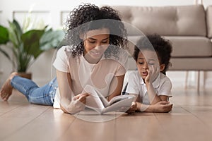 Young black mom reading book with son at home