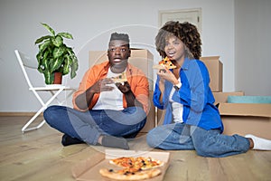 Young Black Spouses Resting On Moving Day, Eating Pizza And Watching Tv