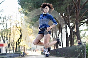 Young black woman with afro hairstyle jumping in urban background