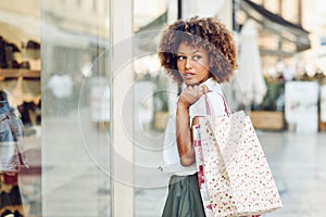 Young black woman, afro hairstyle, looking at a shop window