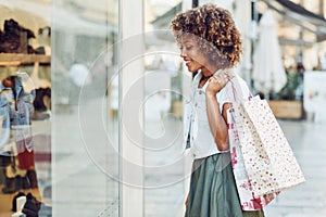 Young black woman, afro hairstyle, looking at a shop window