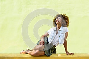 Young black woman, afro hairstyle, sitting on an urban wall