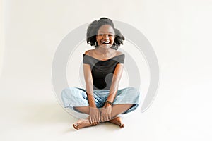 Young black woman with afro hairstyle smiling. Girl wearing black. Studio shot