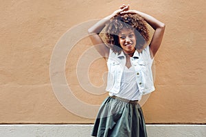 Young black woman, afro hairstyle, smiling in urban background