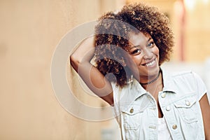 Young black woman, afro hairstyle, smiling in urban background