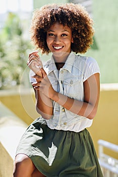 Young black woman, afro hairstyle, smiling in urban background