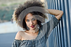 Young black woman with afro hairstyle smiling in urban background