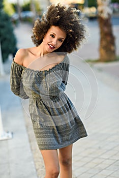 Young black woman with afro hairstyle smiling in urban background