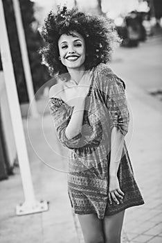 Young black woman with afro hairstyle smiling in urban background