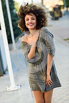 Young black woman with afro hairstyle smiling in urban background