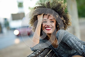 Young black woman with afro hairstyle smiling in urban background