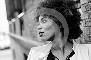 Young black woman with afro hairstyle standing in urban background