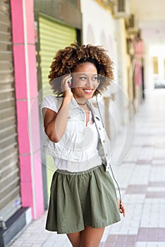 Young black woman, afro hairstyle, in urban street with headphones