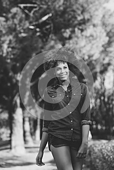 Young black woman with afro hairstyle walking in urban park