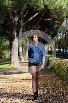 Young black woman with afro hairstyle walking in urban park