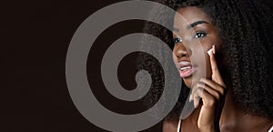 Young black woman applying face cream isolated on background. Banner