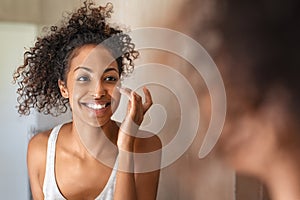 Young black woman applying skin cream photo