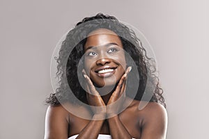 Young black woman applying moisturizer cream on her face