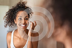 Young black woman applying skin cream