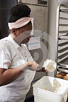 Young black woman at a bakery preparing cake frosting