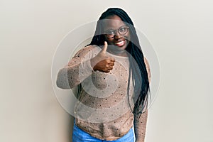 Young black woman with braids wearing casual clothes and glasses doing happy thumbs up gesture with hand