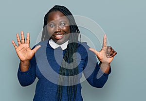 Young black woman with braids wearing casual clothes showing and pointing up with fingers number seven while smiling confident and