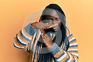 Young black woman with braids wearing casual winter sweater doing time out gesture with hands, frustrated and serious face