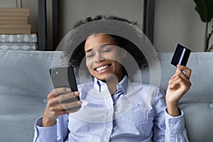 Young black woman check credit card balance online via phone