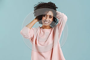 Young black woman with curly hair smiling and holding her head