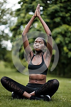 Young black woman doing meditation and yoga in a park