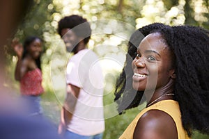 Young black woman in a forest with friends turning to camera