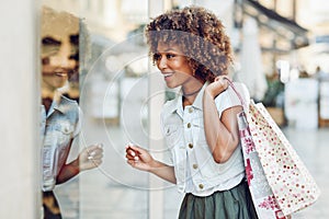 Young black woman, afro hairstyle, looking at a shop window