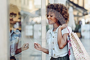 Young black woman, afro hairstyle, looking at a shop window