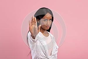 Young black woman gesturing STOP on pink studio background