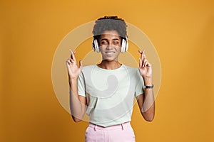 Young black woman with headphones making wish and crossing her fingers