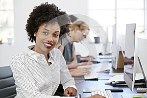 Young black woman with headset smiling to camera in office