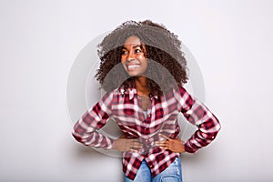 Young black woman laughing with hands on hips and looking away on white background