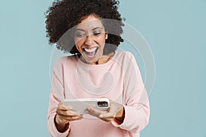 Young black woman laughing and playing online game on cellphone