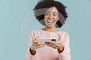 Young black woman laughing and playing online game on cellphone