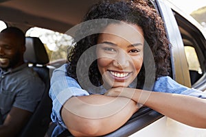 Young black woman looking out of car window smiles to camera