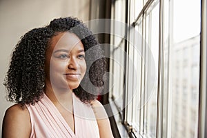 Young black woman looking out of window smiling, close up