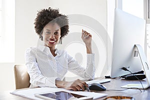 Young black woman in an office smiling to camera, close up