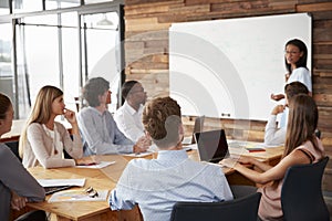 Young black woman presenting to colleagues from whiteboardï¿½