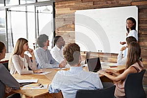Young black woman presenting to colleagues from whiteboardÃ¯Â¿Â½ photo
