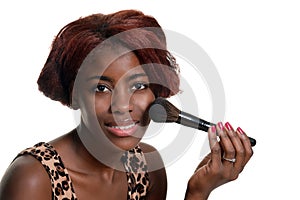 Young black woman putting on blush makeup